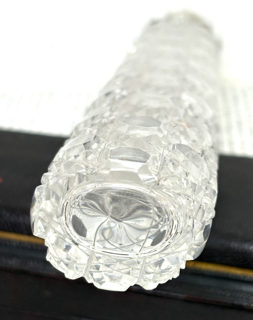 An elongated Victorian cut glass scent bottle with a silver cap resting inside an open velvet and silk lined presentation case. View VIII