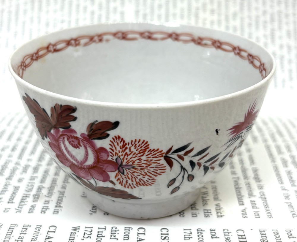 A Georgian Lowestoft white soft-paste porcelain tea bowl with hand-painted floral motifs and a reddish-brown internal chain border. View II
