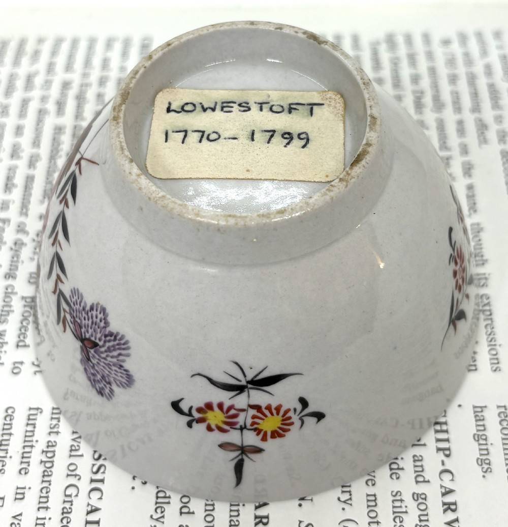 A Georgian Lowestoft white soft-paste porcelain tea bowl with hand-painted floral motifs and a reddish-brown internal chain border. View V
