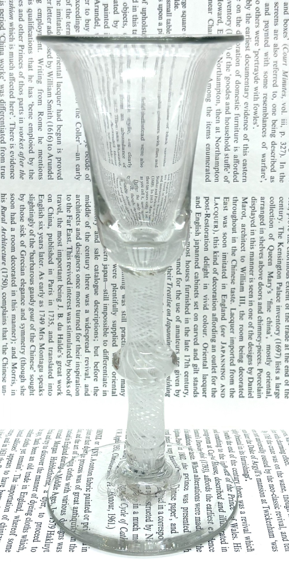 An antique clear glass wine goblet featuring a flared fluted bowl, a central knopped stem with an internal white opaque twist, and a flat circular foot.