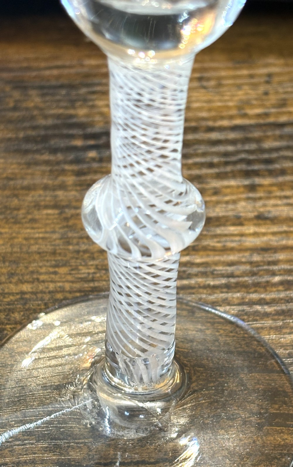 An antique clear glass wine goblet featuring a flared fluted bowl, a central knopped stem with an internal white opaque twist, and a flat circular foot. View III