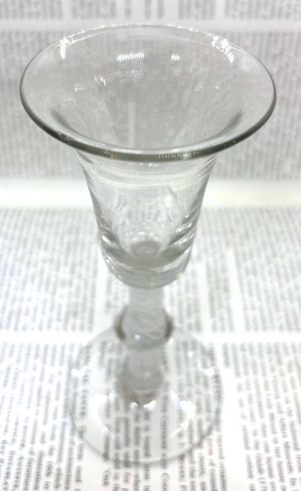 An antique clear glass wine goblet featuring a flared fluted bowl, a central knopped stem with an internal white opaque twist, and a flat circular foot. View IV