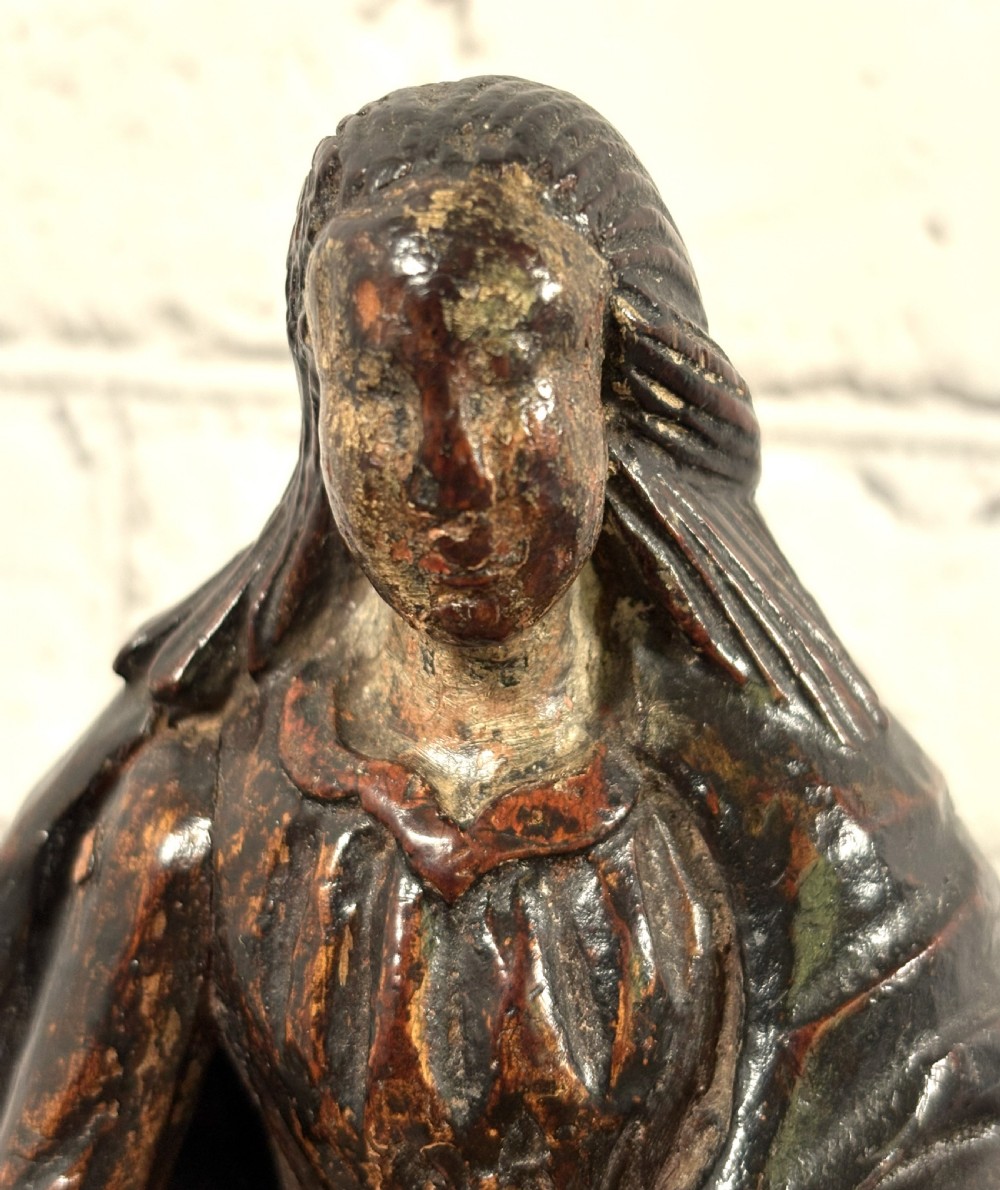 A 17th-century carved limewood figure of a female saint featuring draped robes, dark brown patina, and an octagonal base. View II