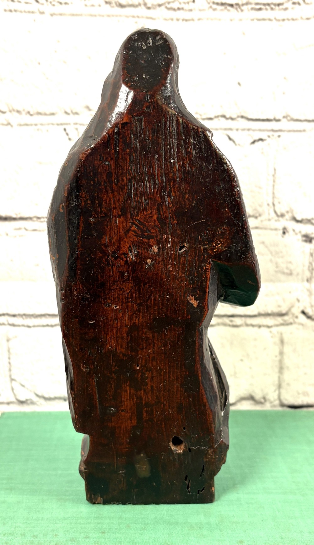 A 17th-century carved limewood figure of a female saint featuring draped robes, dark brown patina, and an octagonal base. View IV