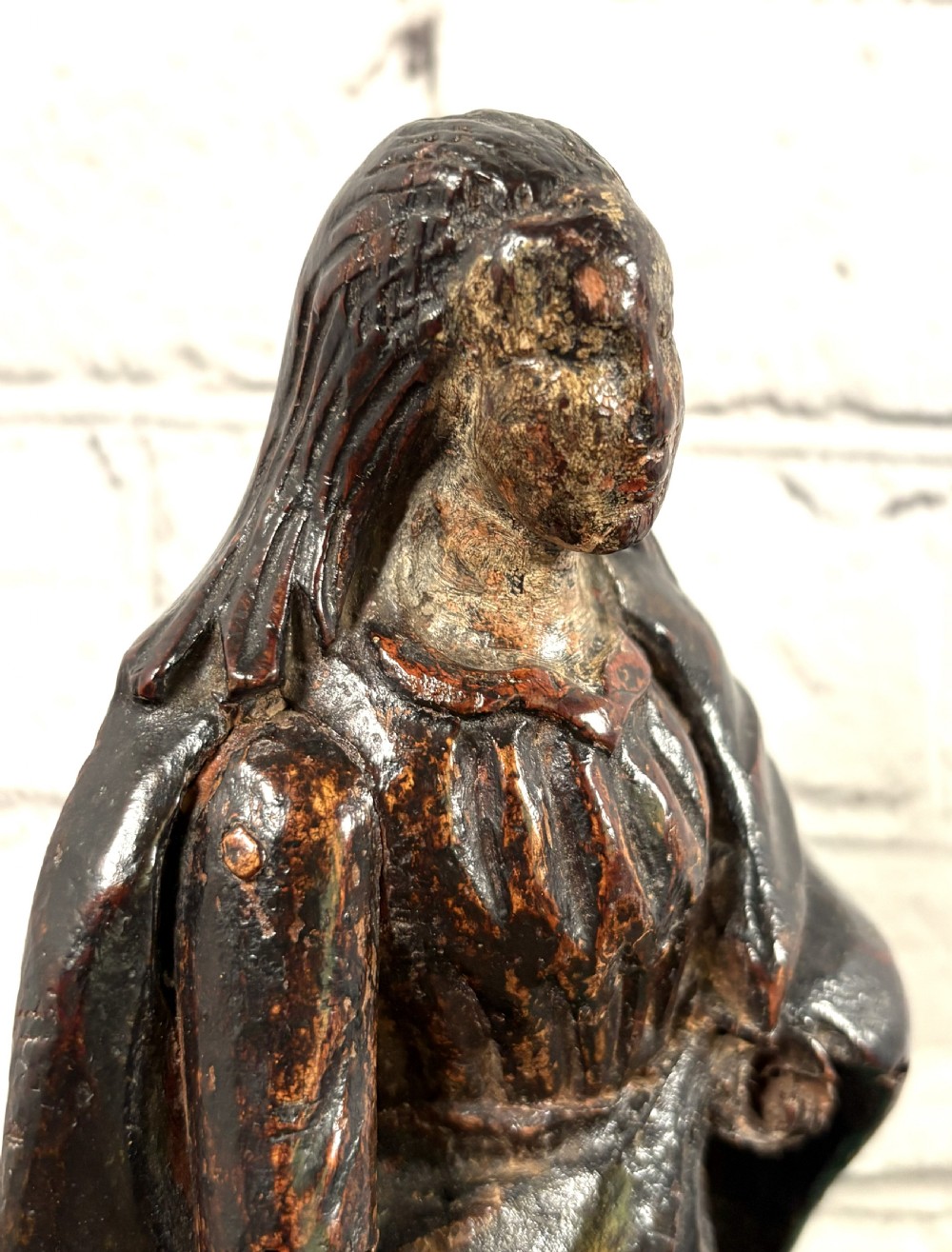 A 17th-century carved limewood figure of a female saint featuring draped robes, dark brown patina, and an octagonal base. View VI