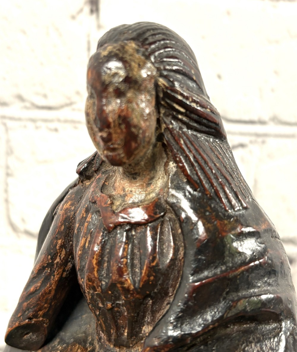 A 17th-century carved limewood figure of a female saint featuring draped robes, dark brown patina, and an octagonal base. View VIII