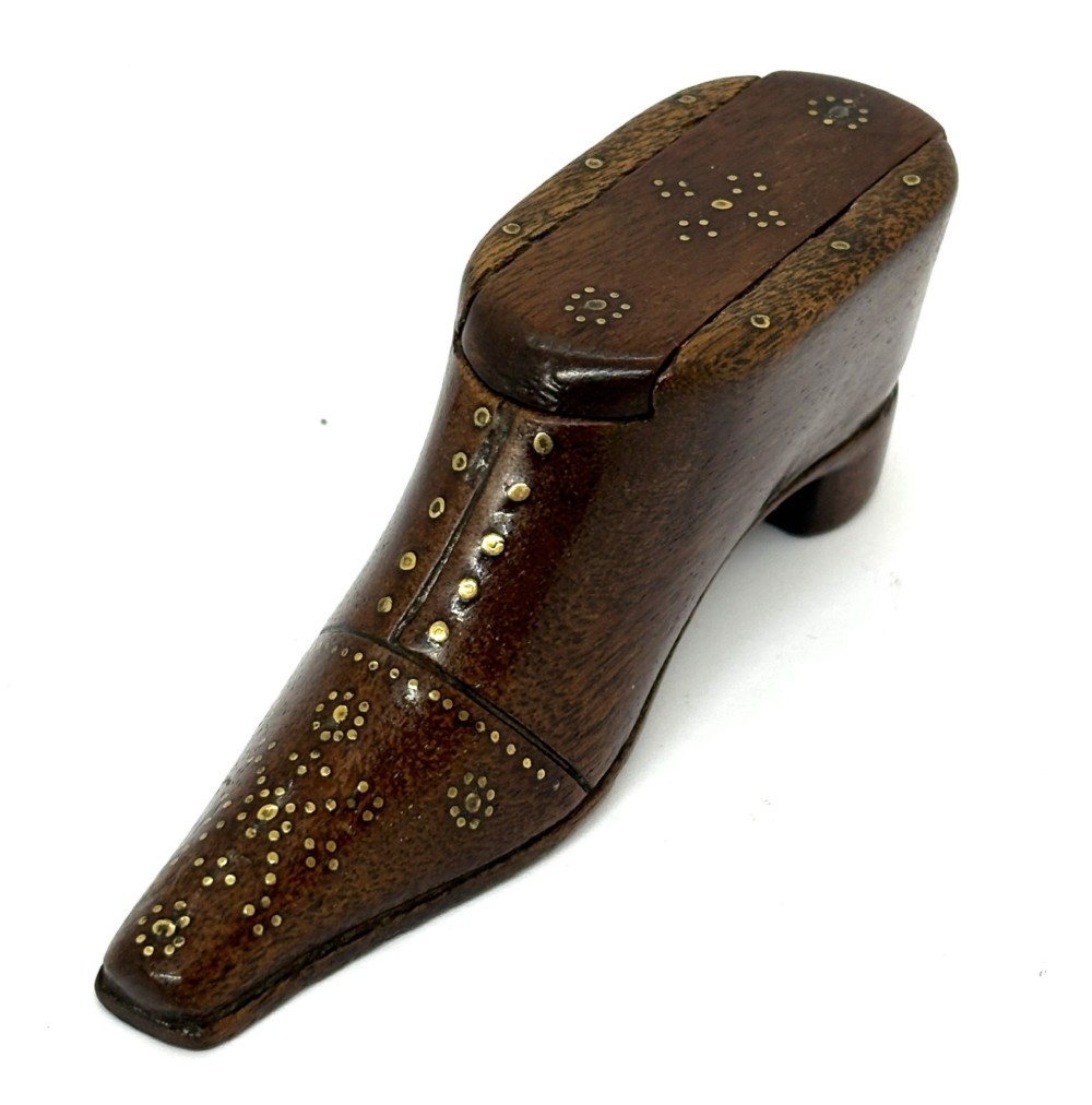 A carved dark wood Georgian snuff box shaped like a shoe with brass pinwork inlay and a sliding top lid.
