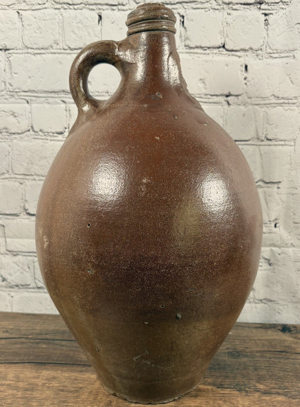 A large brown salt-glazed stoneware jug featuring a bulbous body and a relief mould of a bearded mask on the narrow neck. View V