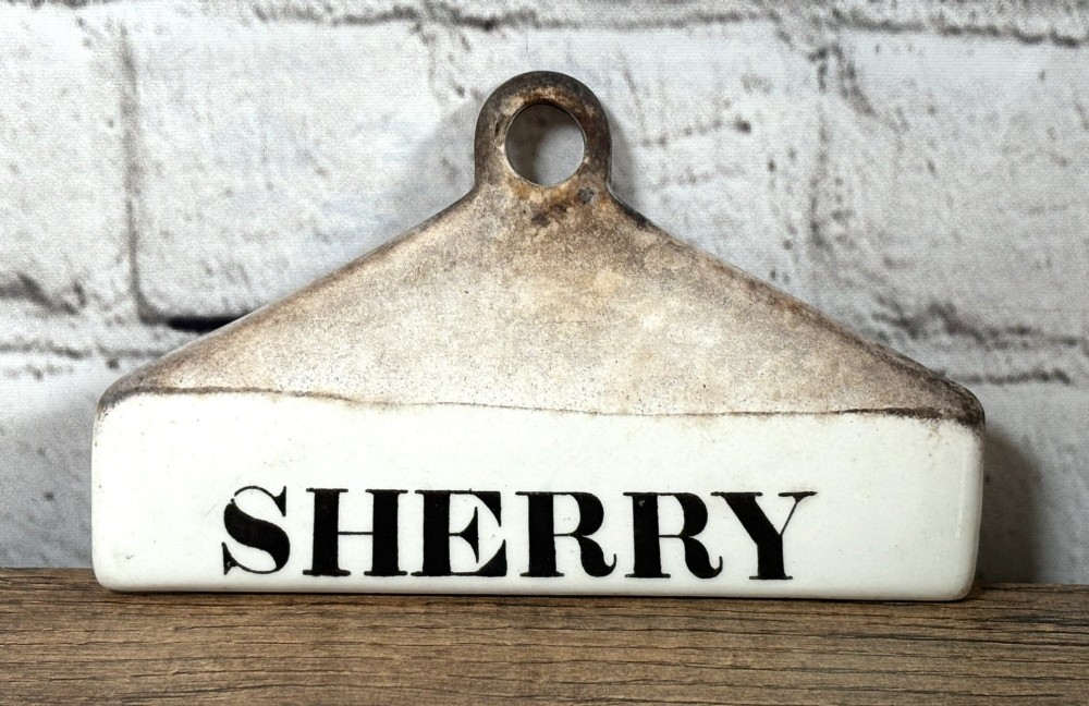 A 19th-century glazed earthenware wine bin label featuring the word SHERRY printed in black typography below a central suspension hole.