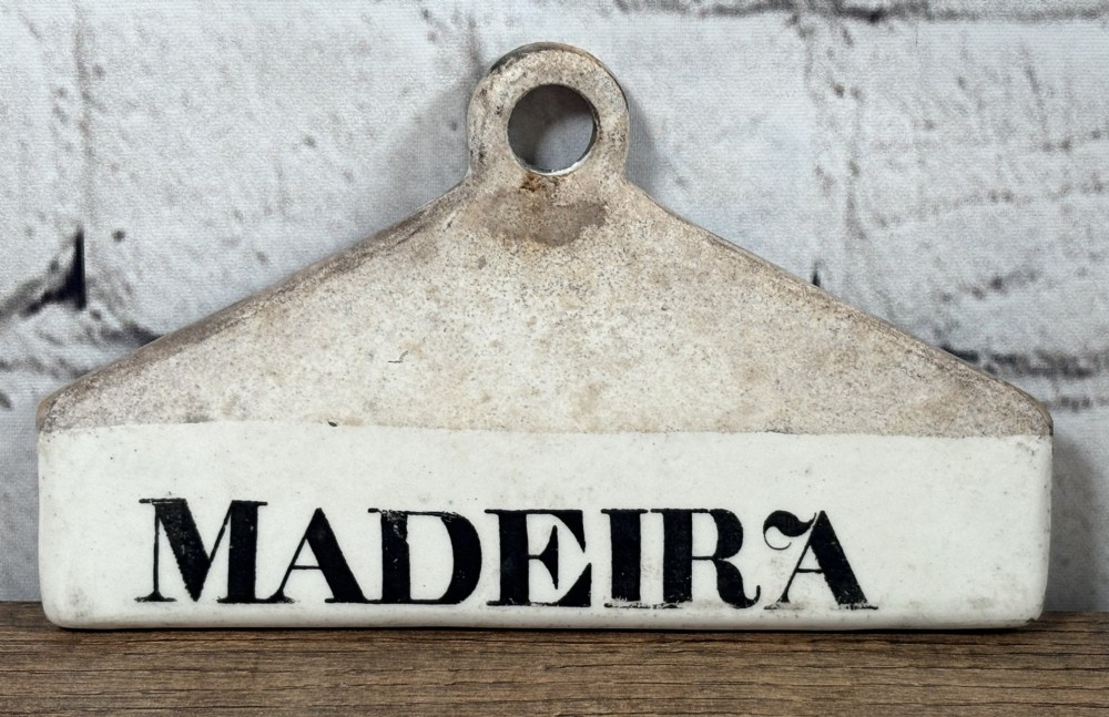 A 19th-century triangular cream ceramic wine bin label with a top hanging hole and black printed lettering reading MADEIRA.