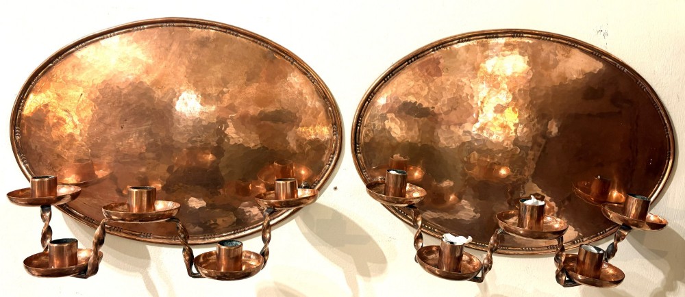 A pair of hand-hammered oval copper wall sconces featuring beaded outer borders and five curved, twisted candle branches.