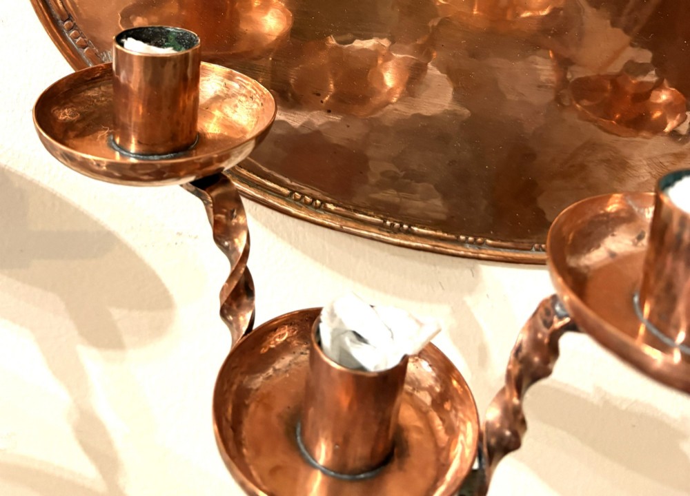 A pair of hand-hammered oval copper wall sconces featuring beaded outer borders and five curved, twisted candle branches. View V