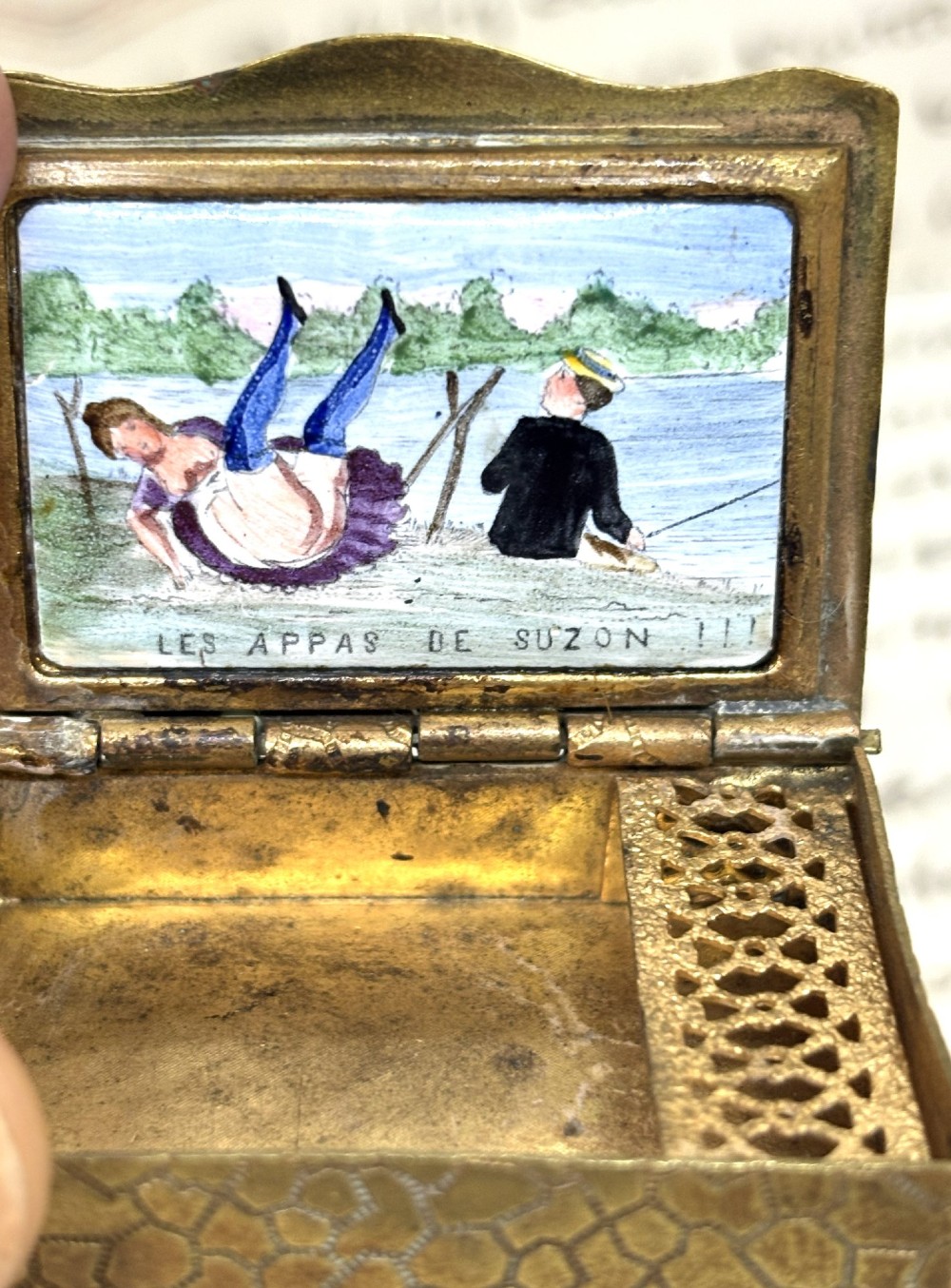 An antique French rectangular brass vesta box featuring an enamelled top panel depicting a lady and a fisherman with French text. View II