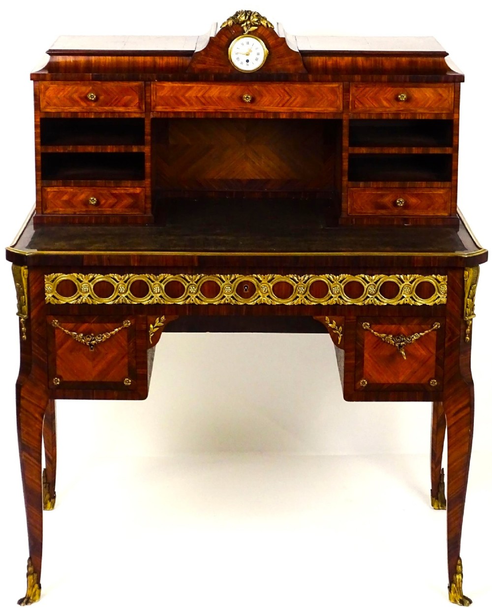 A French 19th-century kingwood writing desk with gilt-bronze ormolu mounts, upper pigeonholes and drawers, a central clock, and cabriole legs.