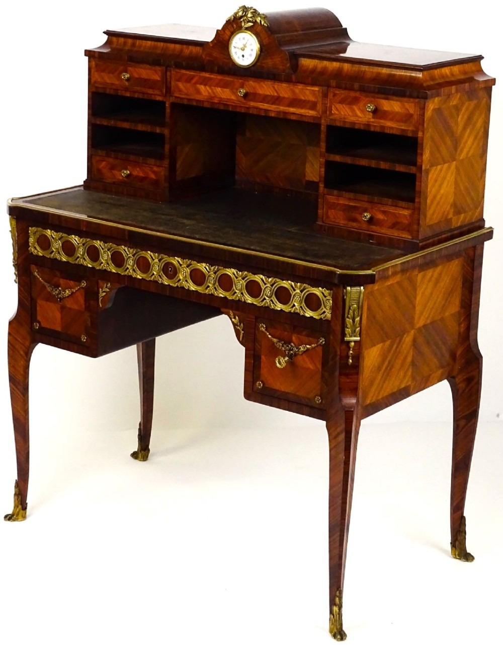 A French 19th-century kingwood writing desk with gilt-bronze ormolu mounts, upper pigeonholes and drawers, a central clock, and cabriole legs. View II