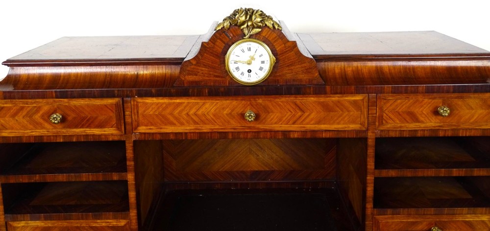 A French 19th-century kingwood writing desk with gilt-bronze ormolu mounts, upper pigeonholes and drawers, a central clock, and cabriole legs. View VIII