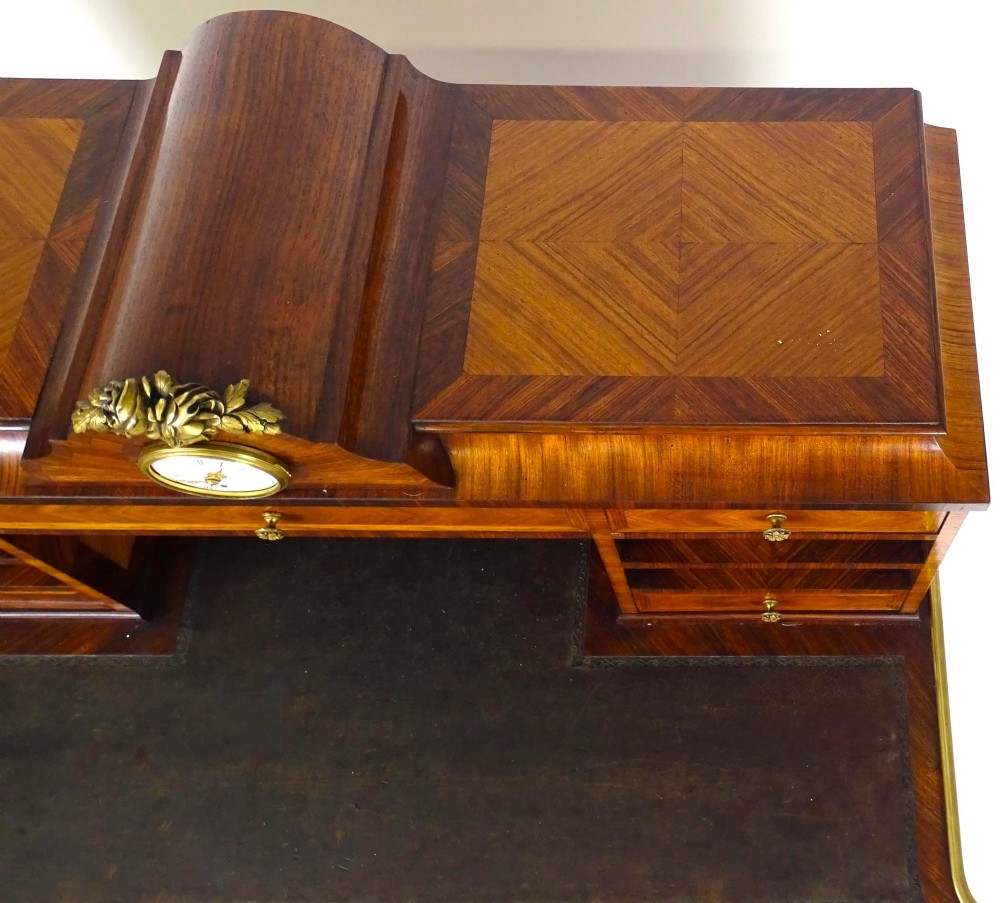 A French 19th-century kingwood writing desk with gilt-bronze ormolu mounts, upper pigeonholes and drawers, a central clock, and cabriole legs. View IX