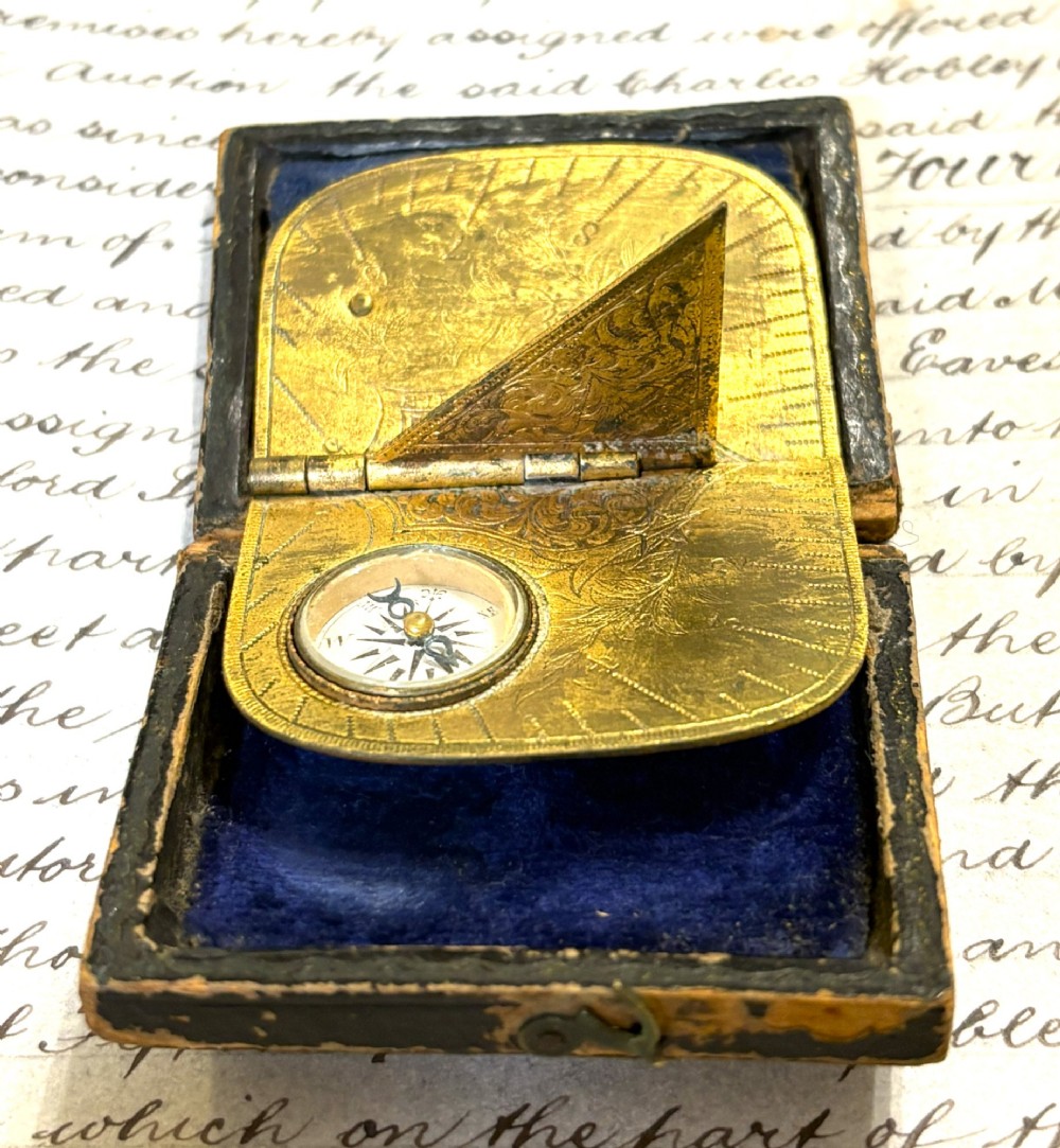 An engraved Victorian brass folding pocket sundial with an integrated compass inside a velvet-lined case. View III