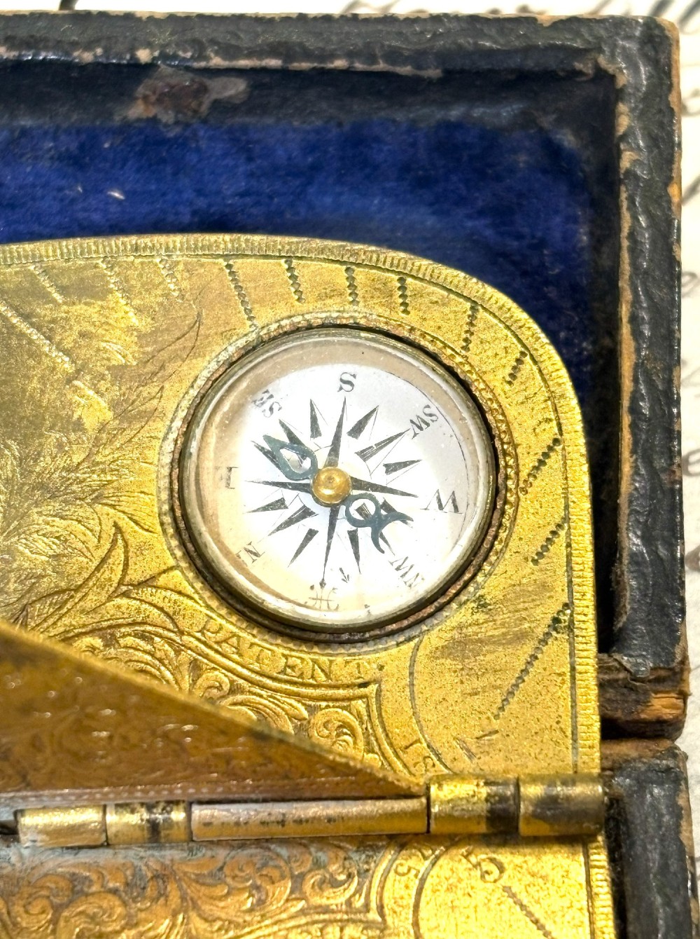 An engraved Victorian brass folding pocket sundial with an integrated compass inside a velvet-lined case. View IV
