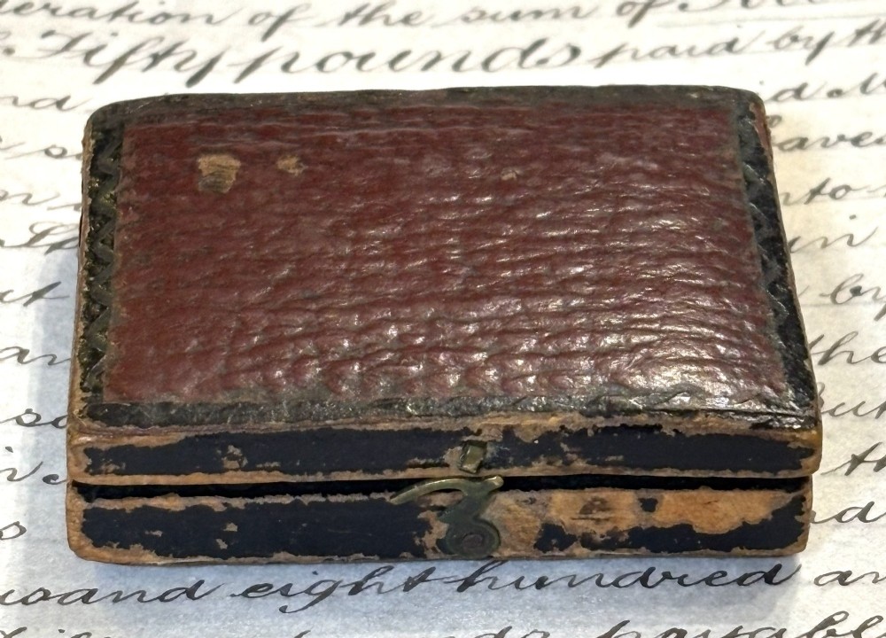 An engraved Victorian brass folding pocket sundial with an integrated compass inside a velvet-lined case. View VII