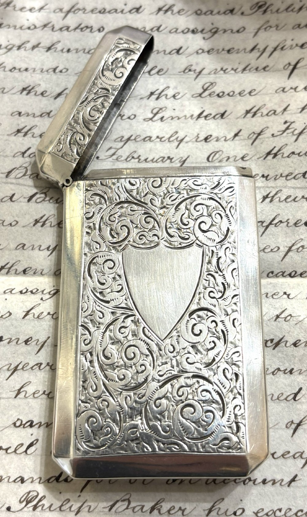 A rectangular Victorian sterling silver card case featuring intricate scroll engraving and an unengraved central heart-shaped shield. View III