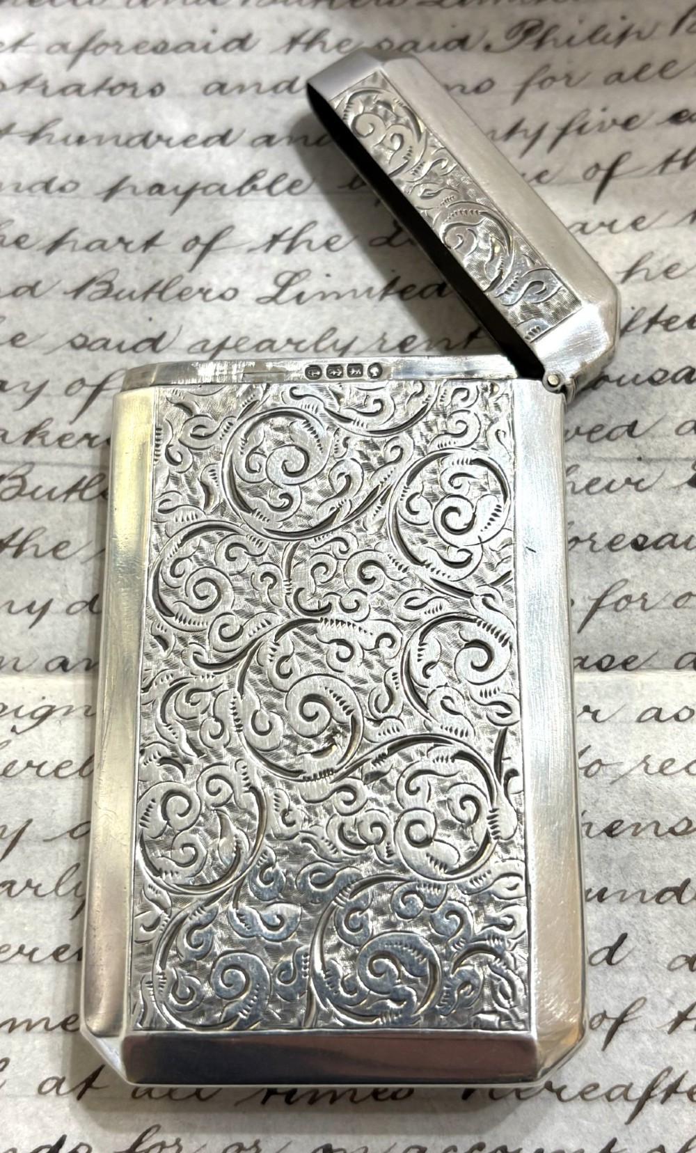 A rectangular Victorian sterling silver card case featuring intricate scroll engraving and an unengraved central heart-shaped shield. View IV