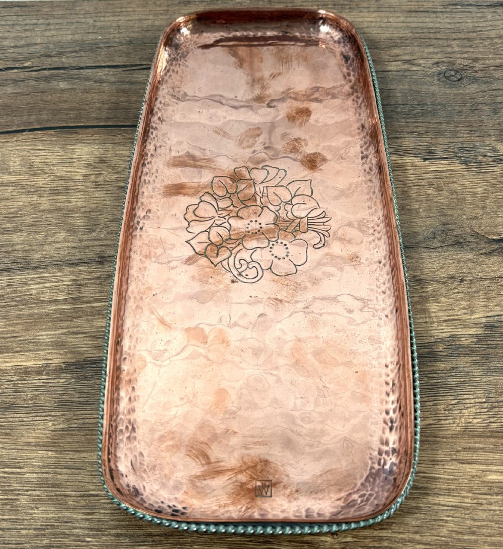 A rectangular hand-hammered copper tray featuring a central engraved floral bouquet motif, a rope-twist pewter rim, and a stamped makers mark signature. View IV