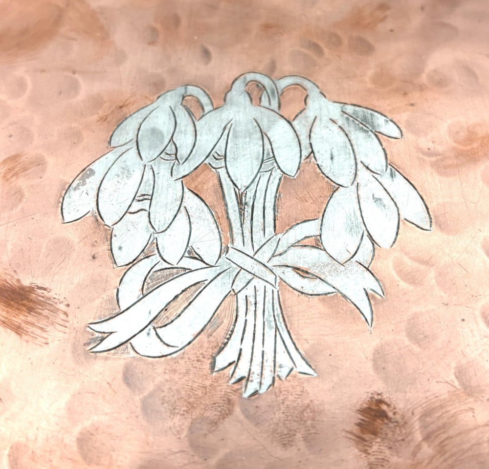 A circular hand-hammered copper tray featuring a pewter inlay of snowdrop flowers tied with a ribbon at the centre. View II