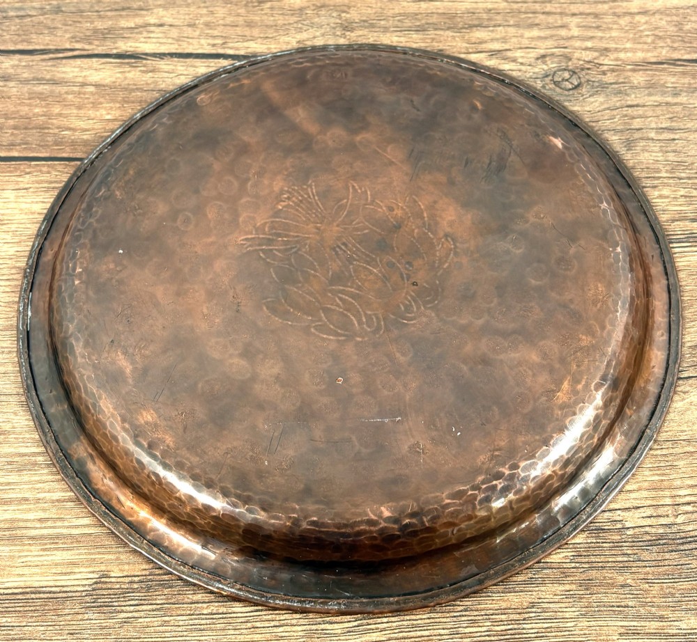 A circular hand-hammered copper tray featuring a pewter inlay of snowdrop flowers tied with a ribbon at the centre. View IV