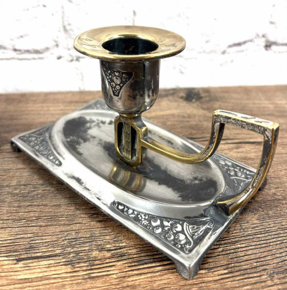A pair of antique Art Nouveau WMF chambersticks crafted from aged silver-coloured metal with brass geometric handles and relief bases. View III