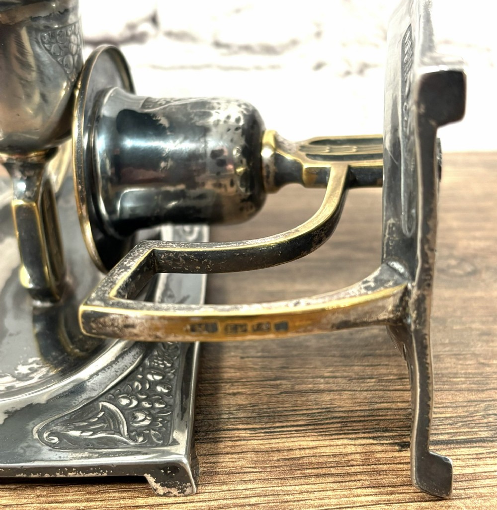 A pair of antique Art Nouveau WMF chambersticks crafted from aged silver-coloured metal with brass geometric handles and relief bases. View VI
