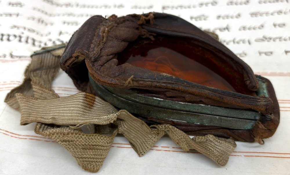 A pair of early 20th-century aviation goggles with amber glass lenses and a fabric strap resting alongside a brown storage case. View IV