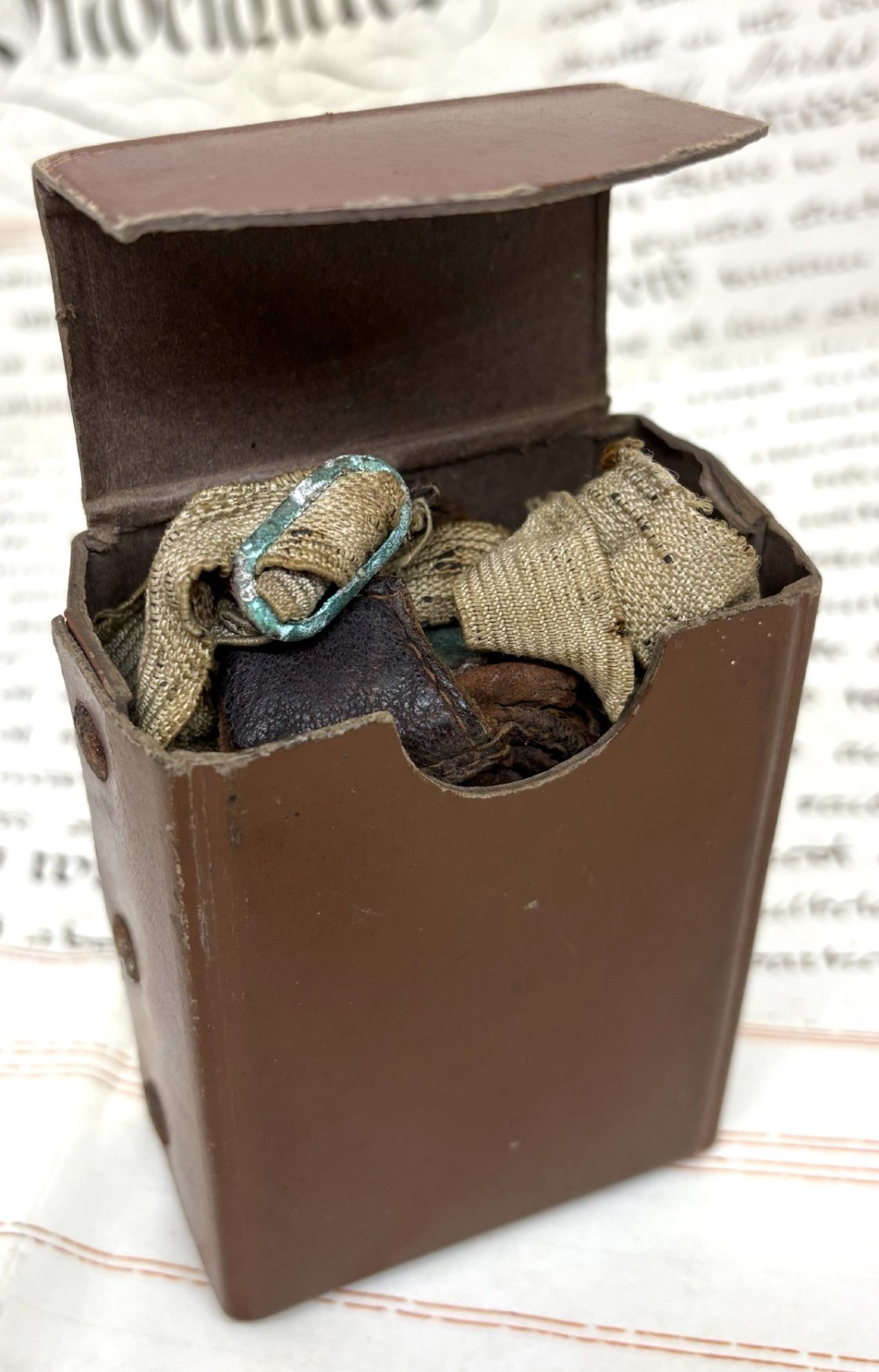 A pair of early 20th-century aviation goggles with amber glass lenses and a fabric strap resting alongside a brown storage case. View V