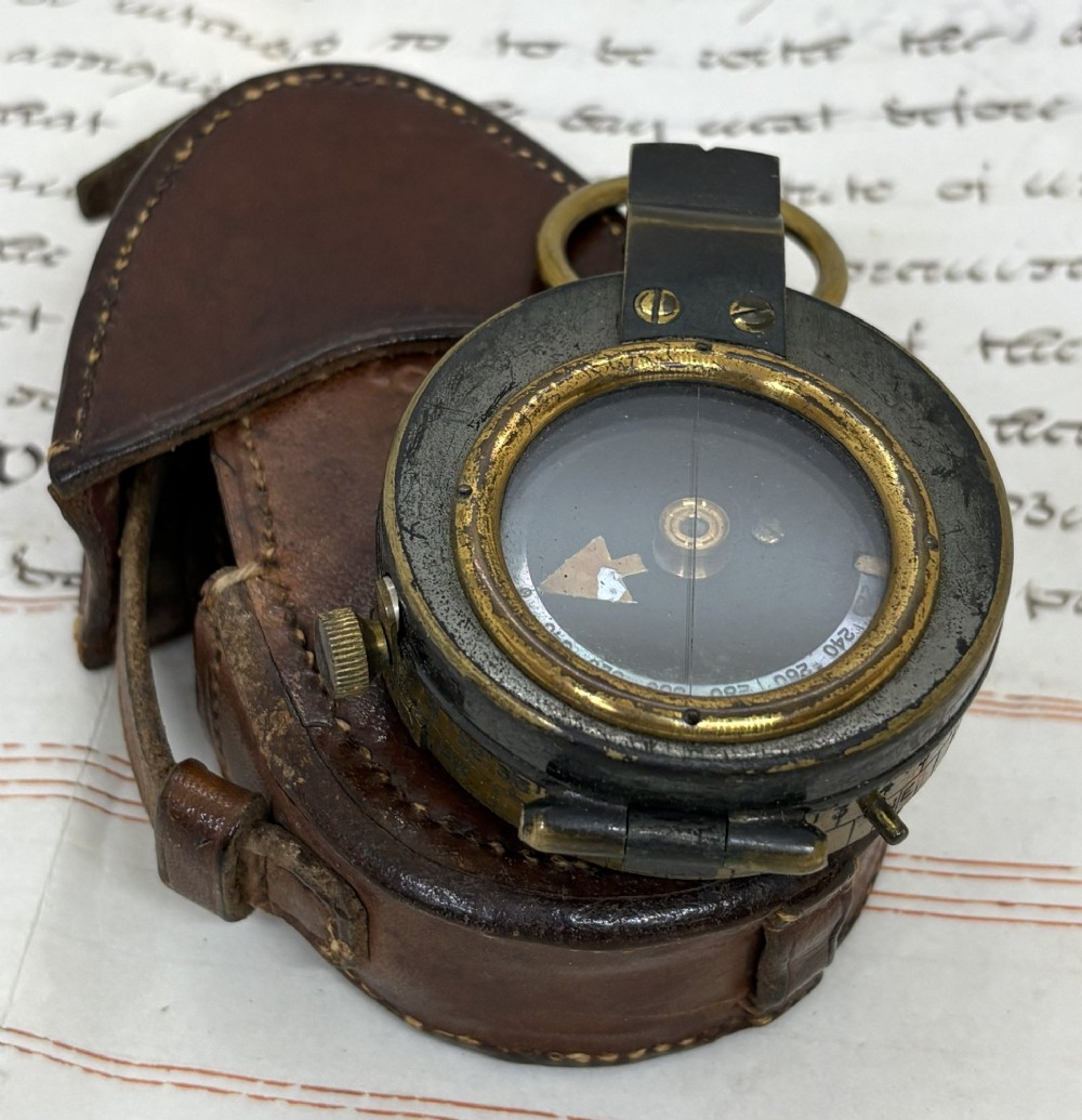 A First World War brass field compass with a patinated brass casing, glass crystal display, and fitted dark brown leather protective case.