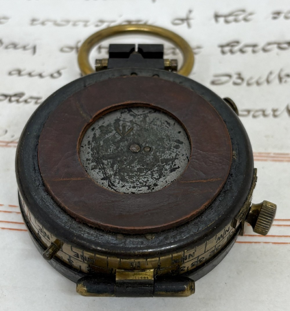 A First World War brass field compass with a patinated brass casing, glass crystal display, and fitted dark brown leather protective case. View III