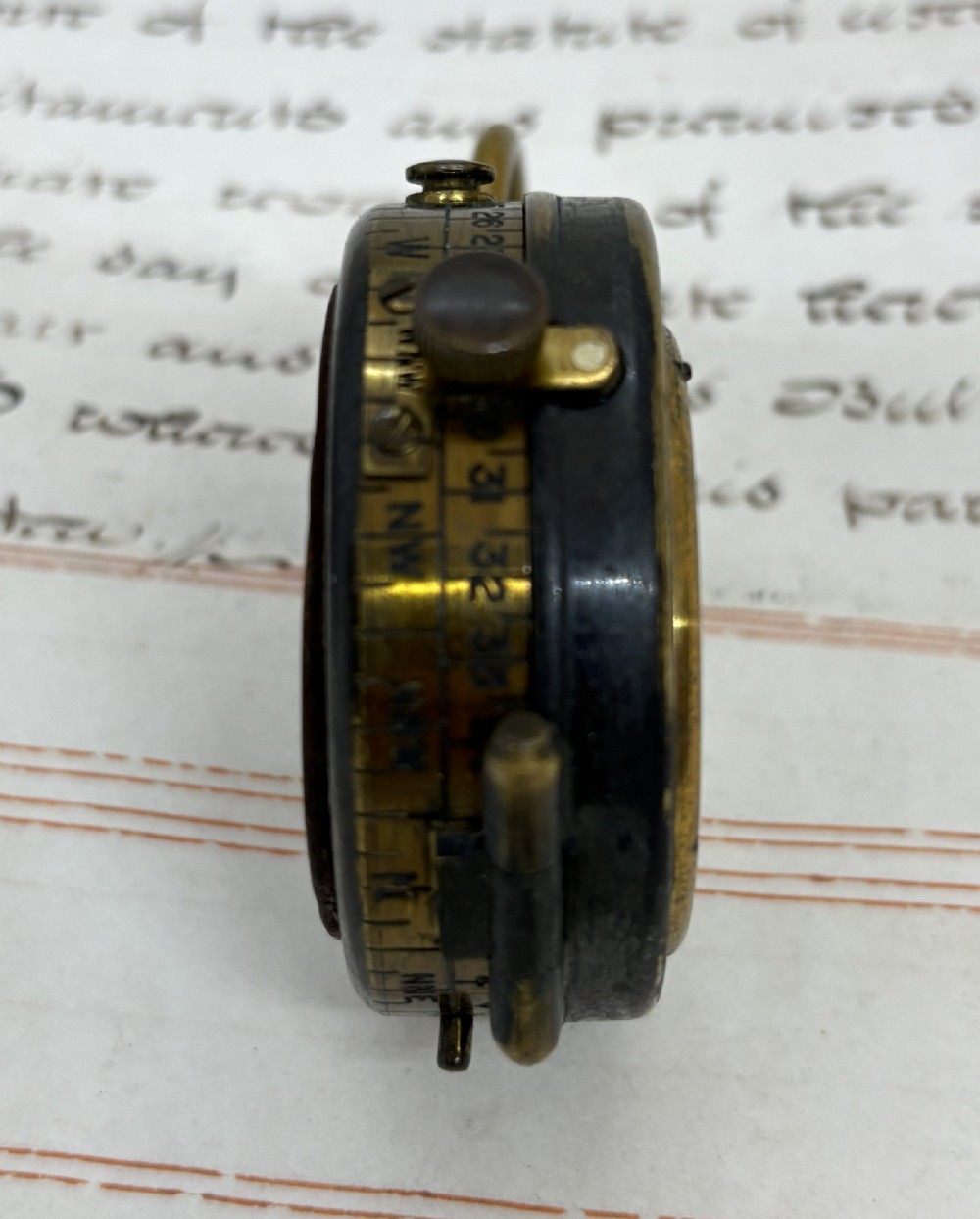 A First World War brass field compass with a patinated brass casing, glass crystal display, and fitted dark brown leather protective case. View IV