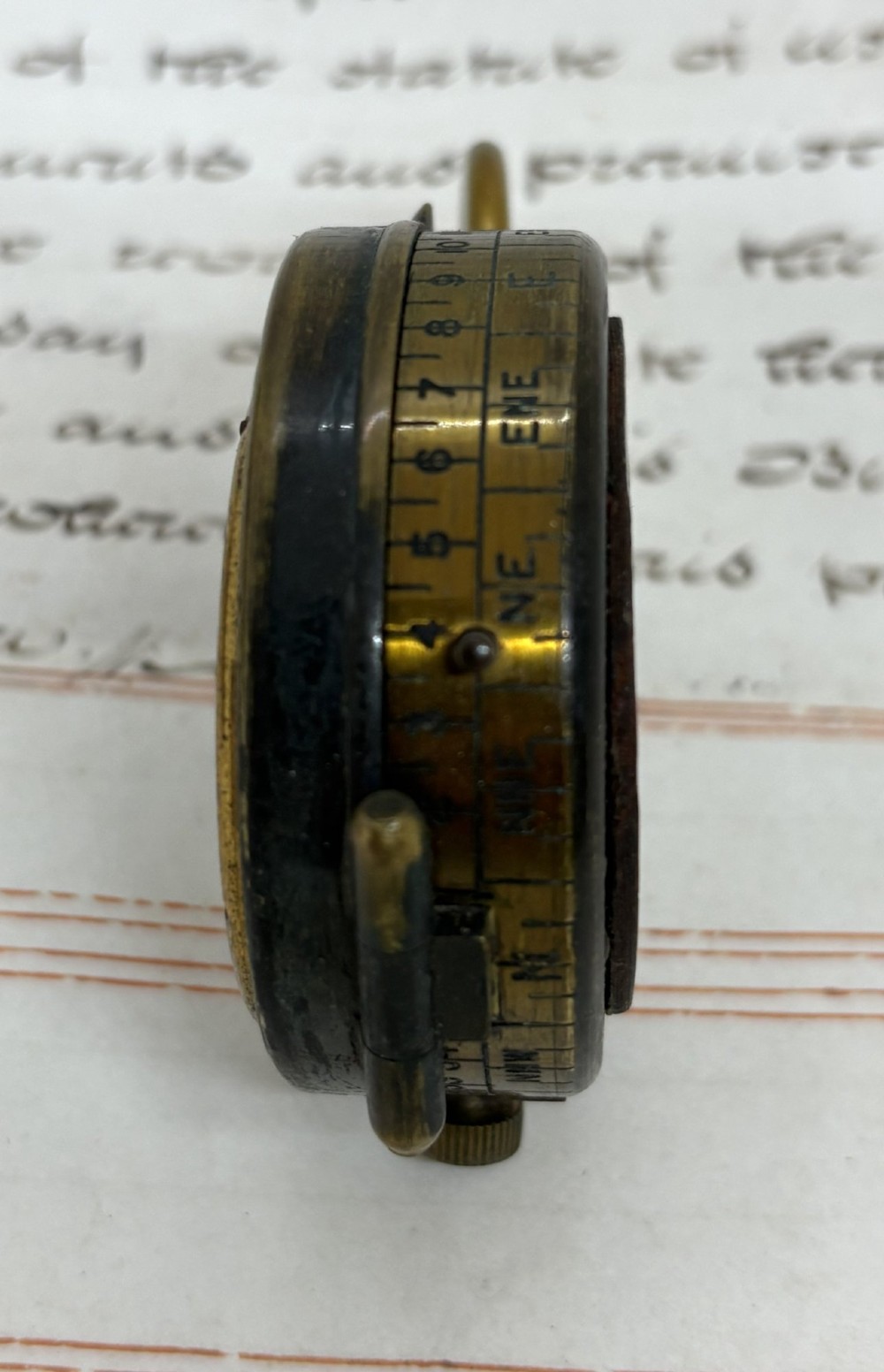 A First World War brass field compass with a patinated brass casing, glass crystal display, and fitted dark brown leather protective case. View V