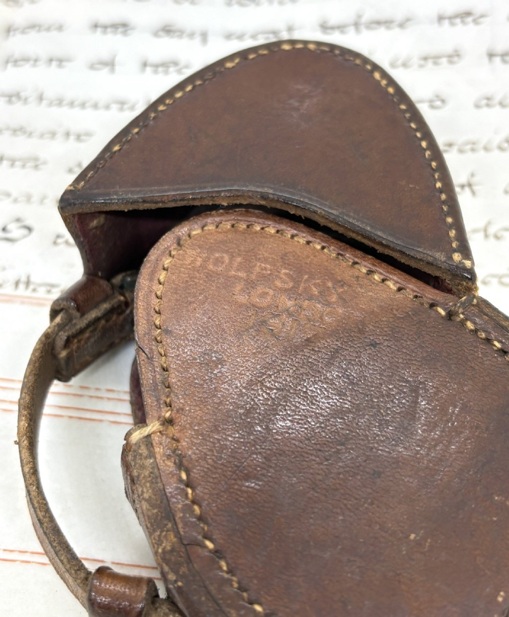 A First World War brass field compass with a patinated brass casing, glass crystal display, and fitted dark brown leather protective case. View VII