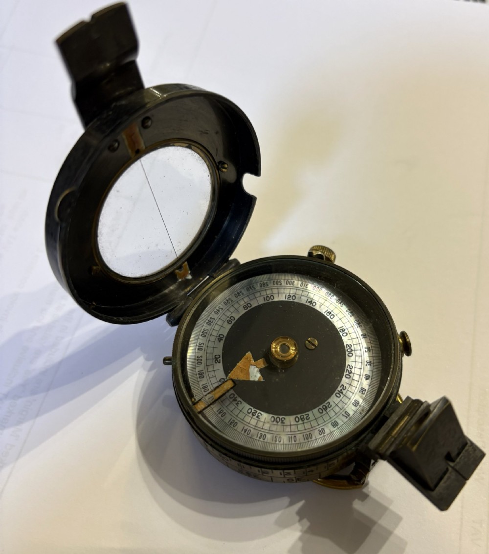 A First World War brass field compass with a patinated brass casing, glass crystal display, and fitted dark brown leather protective case. View VIII