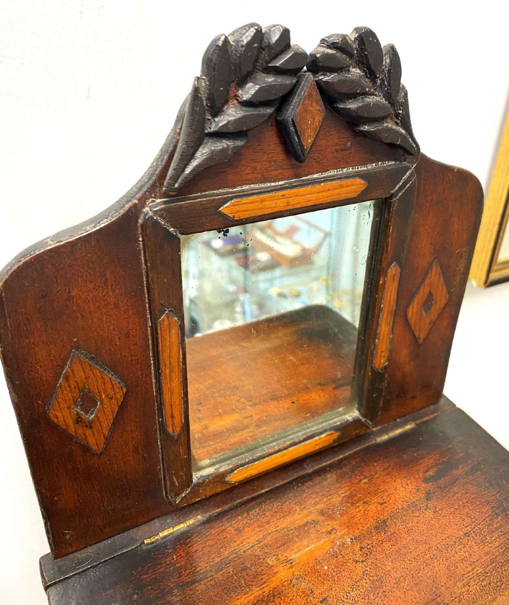 A Victorian miniature mahogany chiffonier featuring a small rectangular mirror, carved leaf cresting, inlaid diamond motifs, and small drawers with turned knobs. View IV