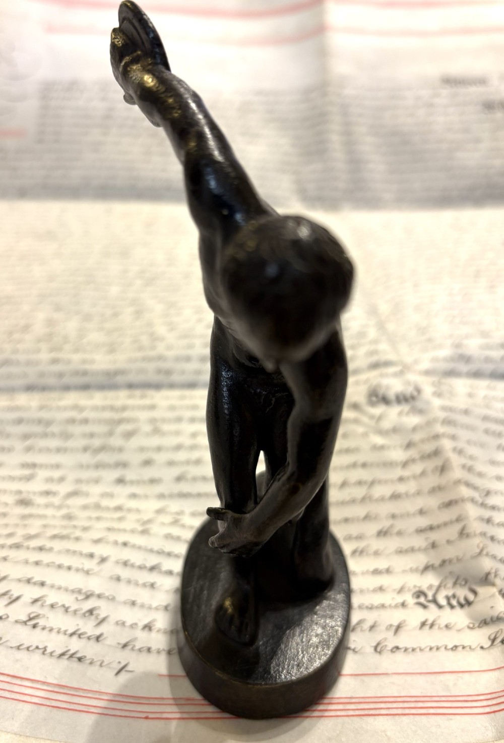 A dark patinated bronze figure depicting a male athlete in the classical Discobolus pose preparing to throw a discus. View III