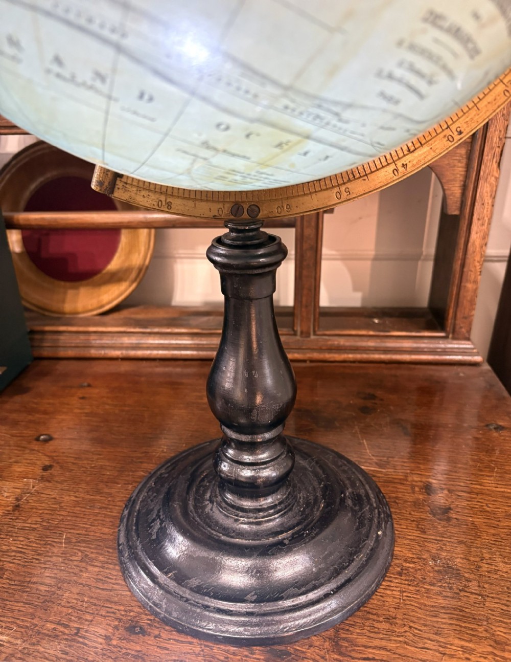 An antique French terrestrial globe featuring yellowed paper gores and pale blue oceans set within a brass meridian ring on an ebonised wooden base. View III