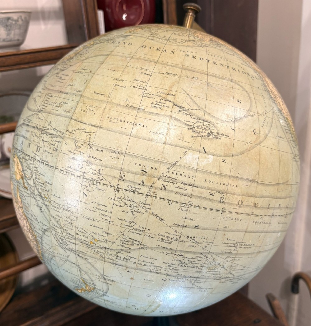 An antique French terrestrial globe featuring yellowed paper gores and pale blue oceans set within a brass meridian ring on an ebonised wooden base. View IV