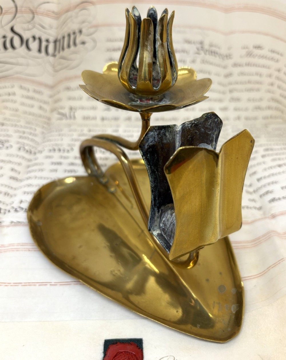 An Art Nouveau brass chamberstick featuring a leaf-shaped tray base, a curved stem supporting a tulip-form candle sconce, and an attached matchbox holder. View II