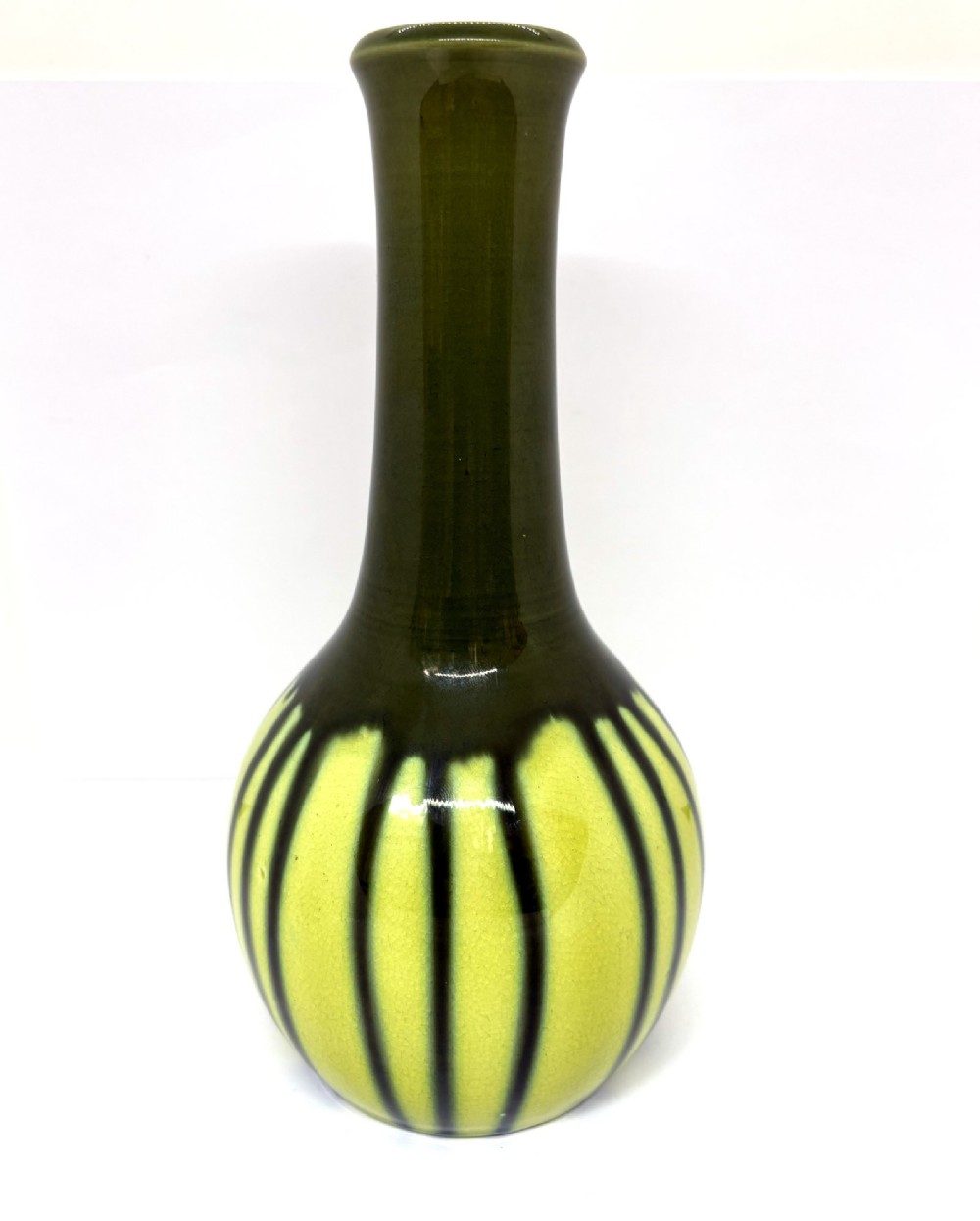 A ceramic vase with a long slender neck and bulbous body displaying vertical dark green drip glaze over a chartreuse background.