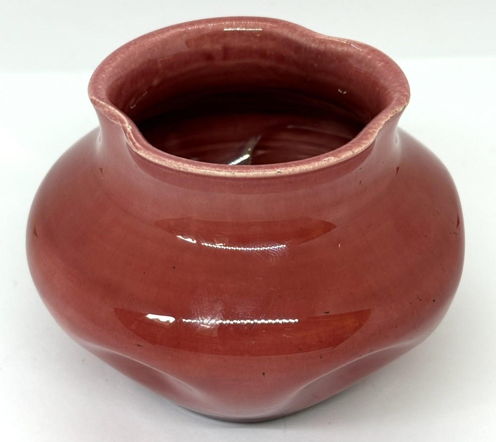 A small squat dusky pink glazed ceramic vase with a lobed rim and bulbous body.