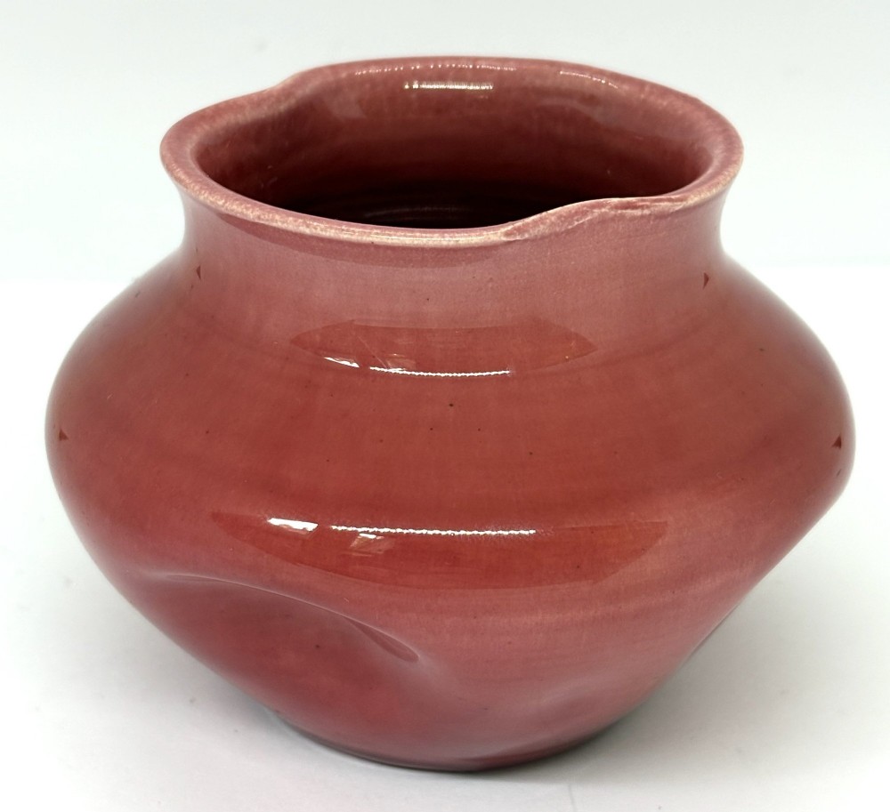 A small squat dusky pink glazed ceramic vase with a lobed rim and bulbous body. View II