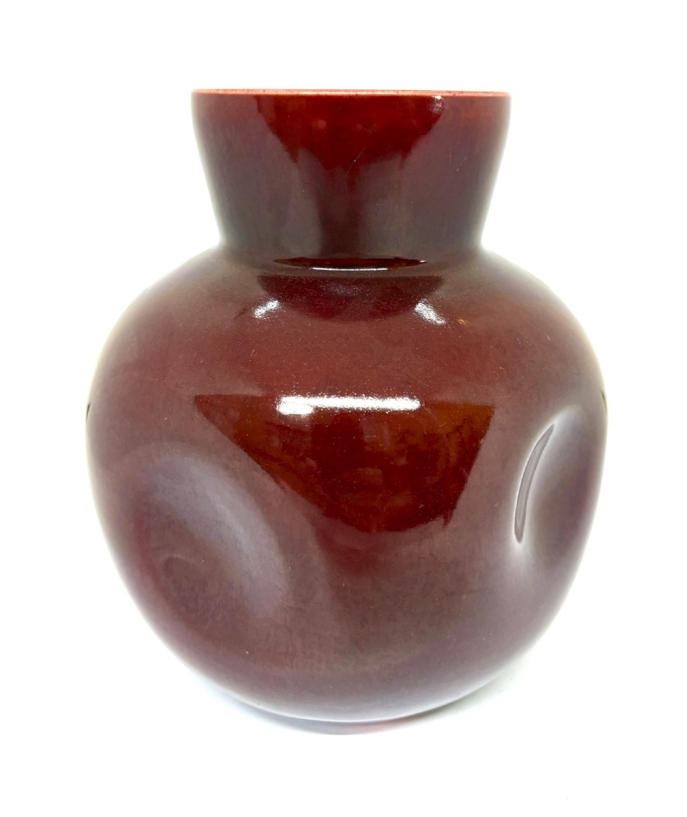 A bulbous ceramic vase with a glossy deep burgundy-brown glaze, indented dimples on the sides, and a short flared neck.