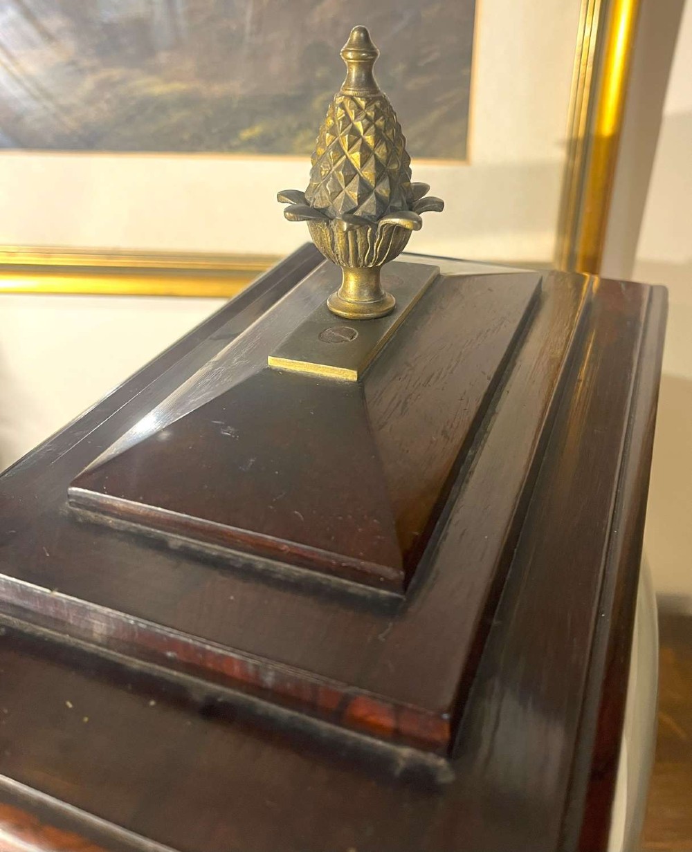 A Regency mahogany bracket clock featuring brass corner inlay, a top pineapple finial, brass ball feet, and a cream painted dial signed P. Ketterer Stamford Hill. View VII