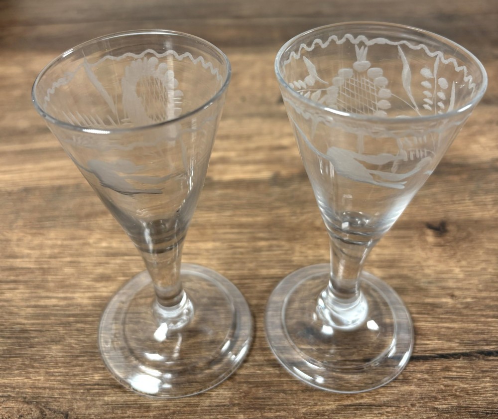 A pair of clear hand-blown Georgian glass drinking vessels featuring flared conical bowls with floral wheel engraving and circular bases. View II